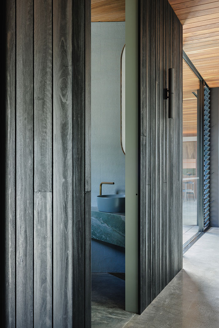 floor to ceiling doorway with black cladded interior walls and stylish bathroom beyond the doorway