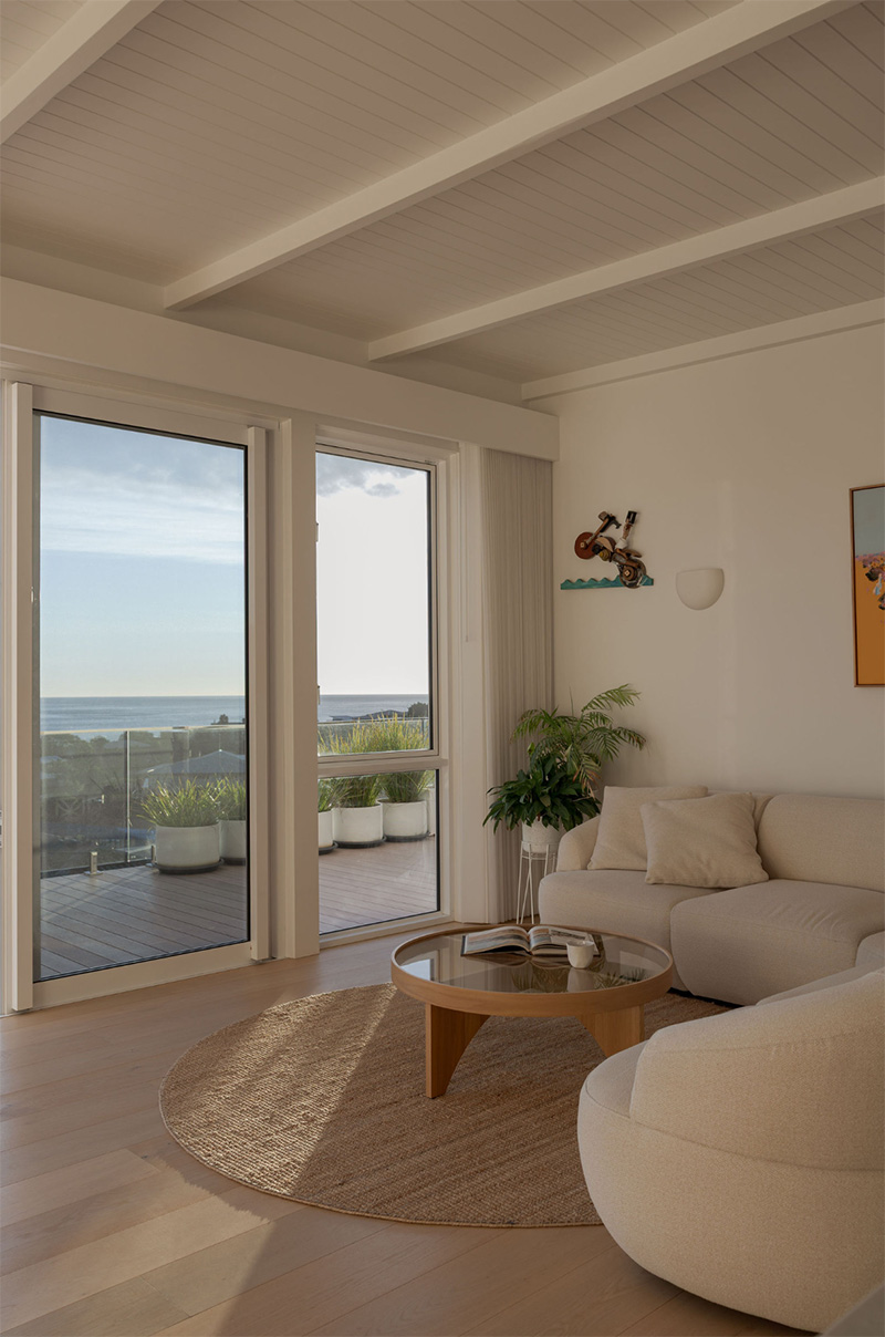 living room features panelled ceiling lining with large format glass doors