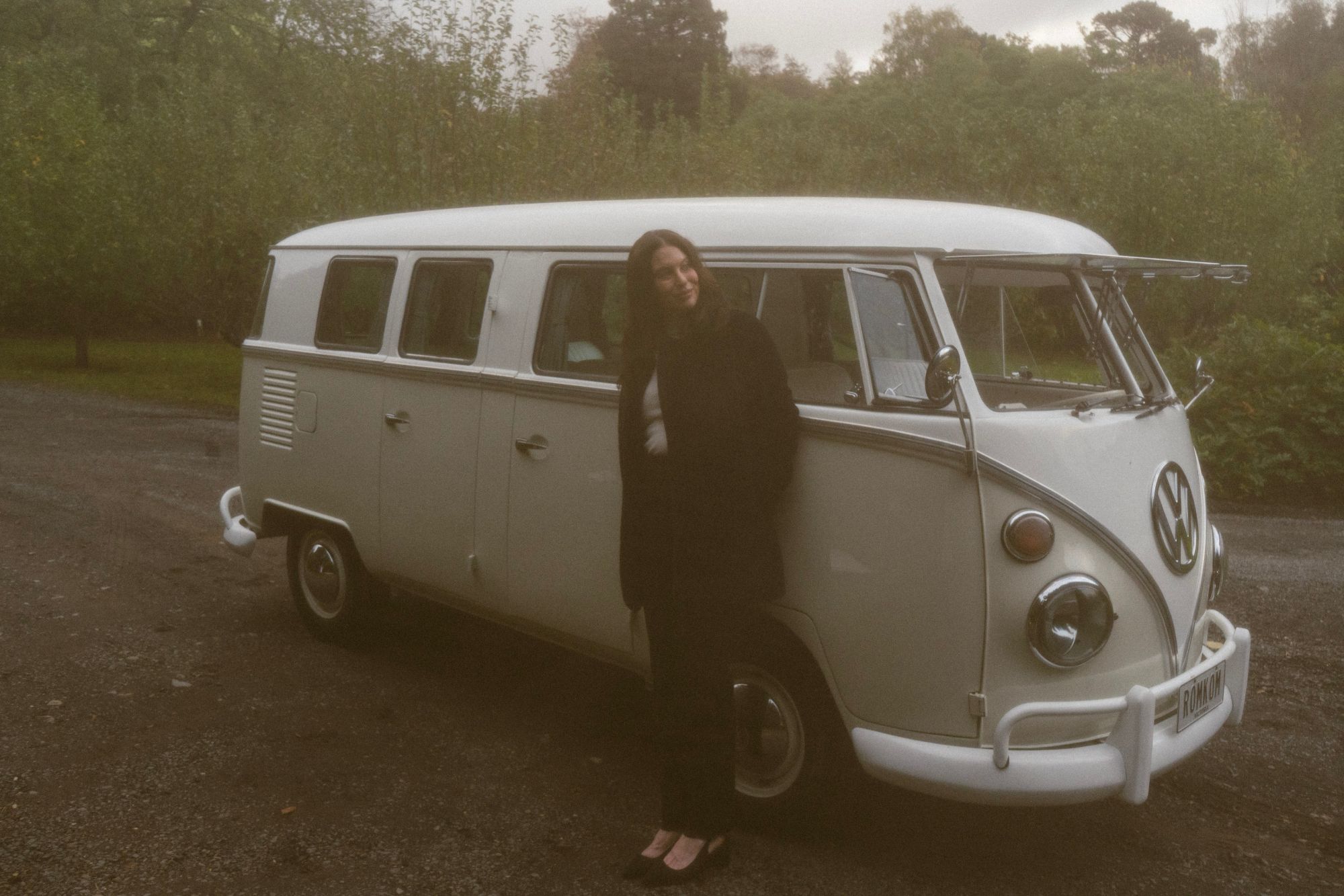 Leaning against the white 1968 RomKom Kombi among the trees