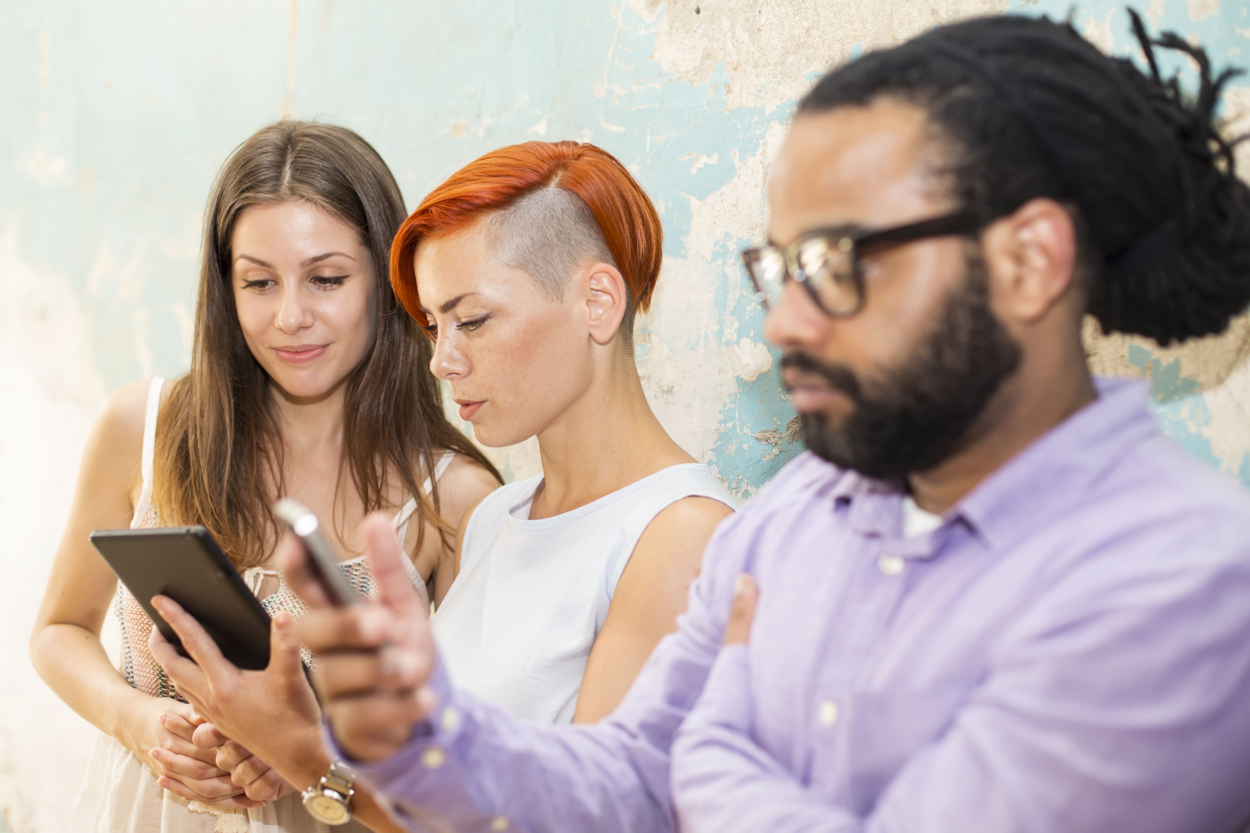 Overhead view of business team joining hands together over a wooden table in a meeting room.