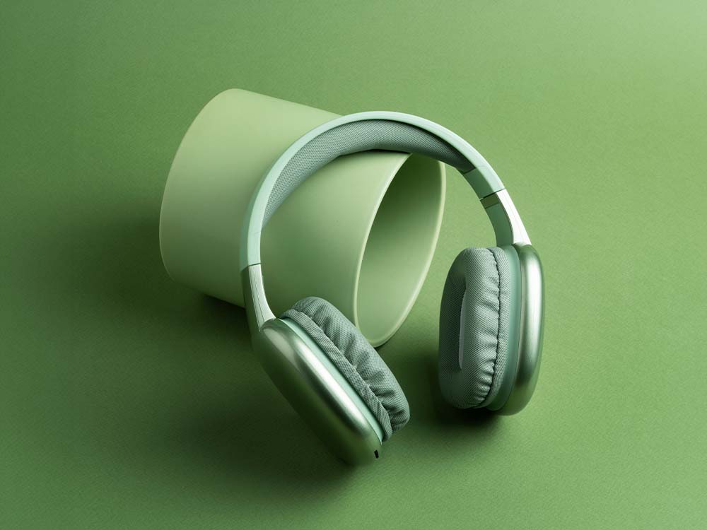 Green headset and green mug on green background.