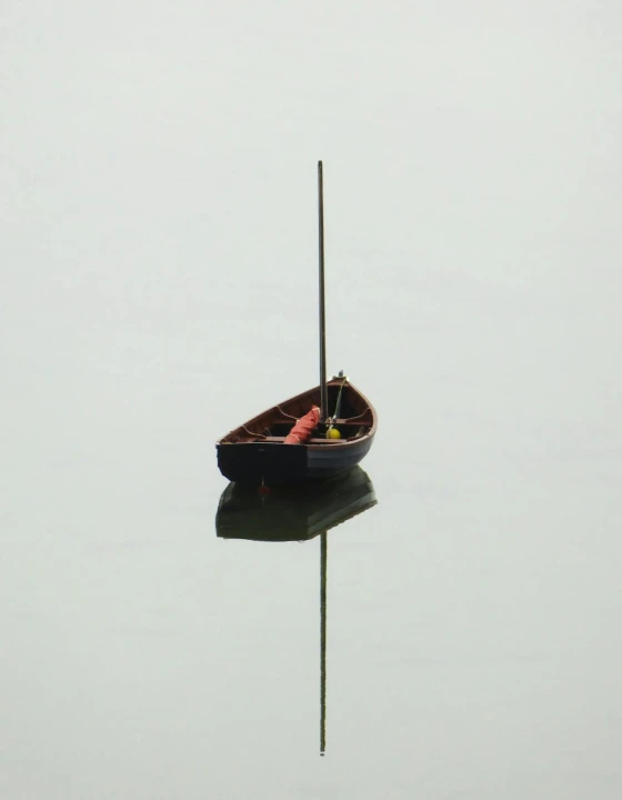 Small boat floating on perfectly still water with a clean mirror reflection.