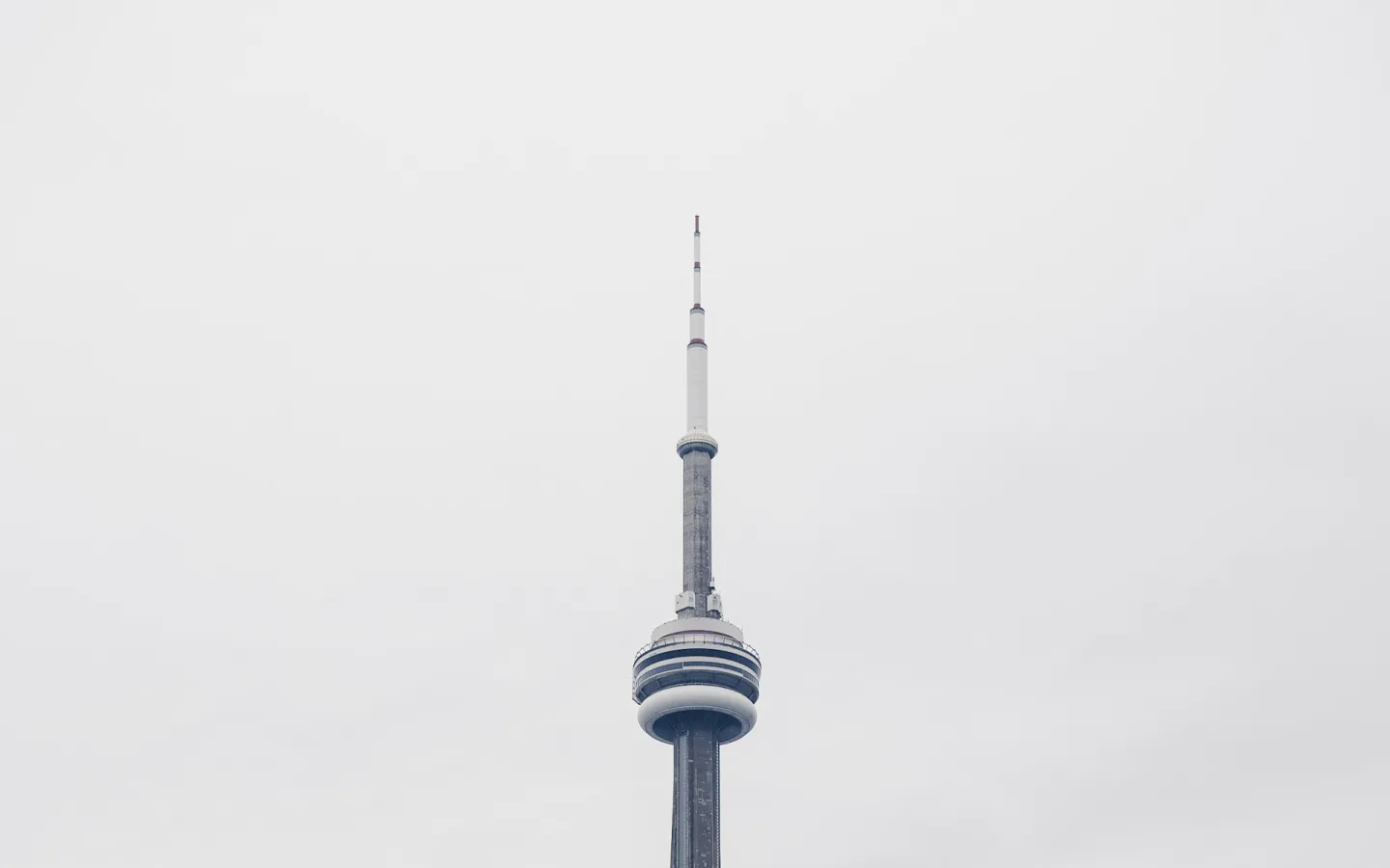 Minimalist view of a tall tower rising into a foggy white sky.