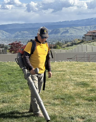 a rooster employee using a blower to complete a lawn maintenance project in sunny slope wenatchee.