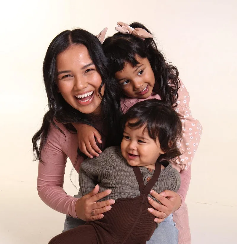 A woman and her kids smiling and laughing while in front of the camera.