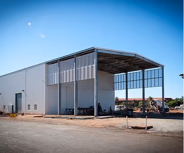 Large industrial warehouse with open side and clear blue sky above it.