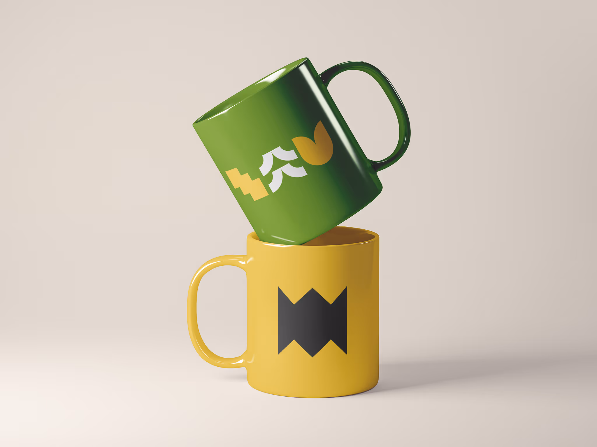 Stacked mugs with a green mug on top featuring geometric shapes in yellow, white, and orange, and a yellow mug below with a black zigzag design.