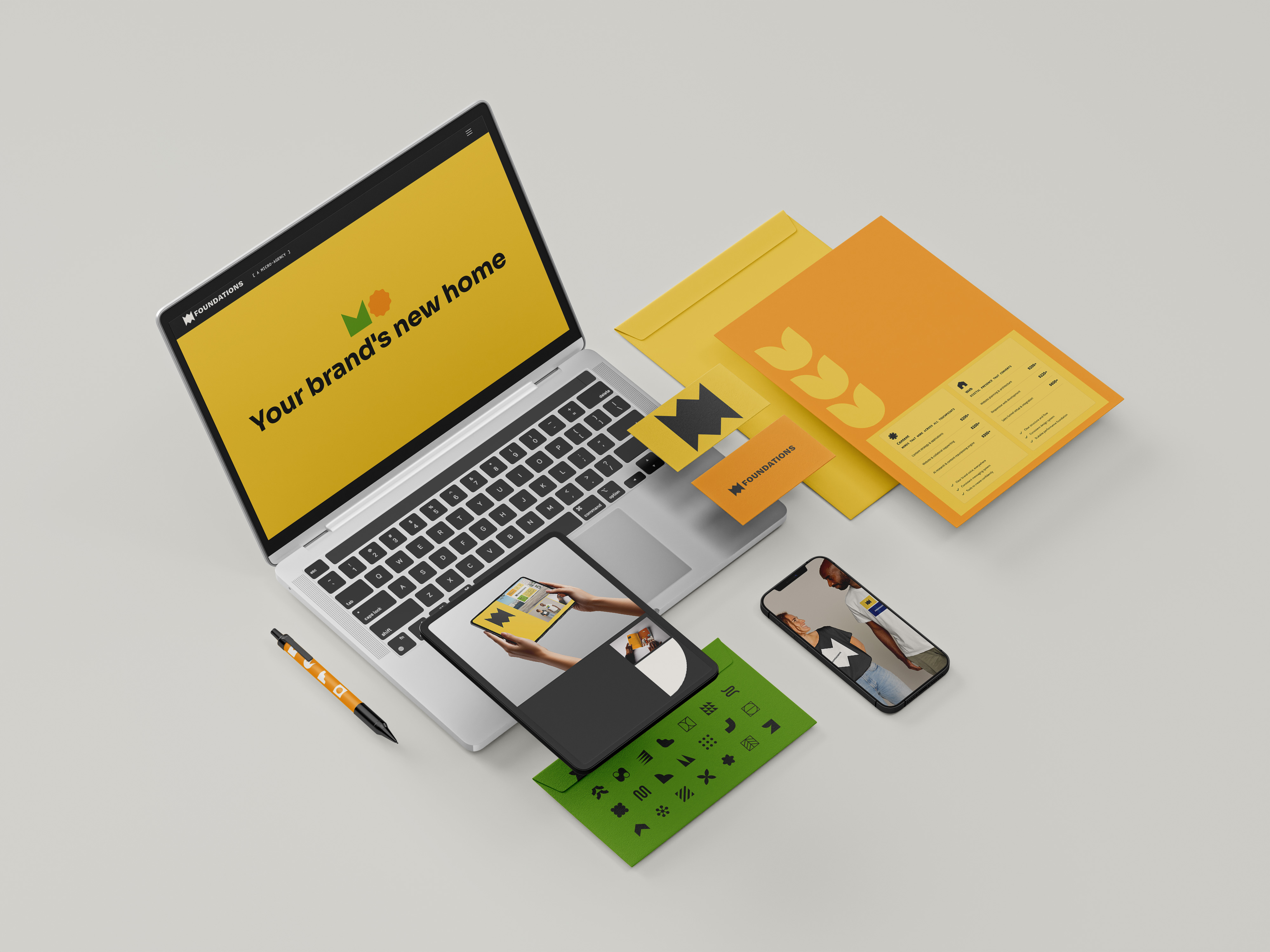 Flat lay of a laptop, tablet, smartphone, folders, business cards, envelopes, and a pen, all featuring colorful branding elements and the text 'Your brand's new home' on the laptop screen.
