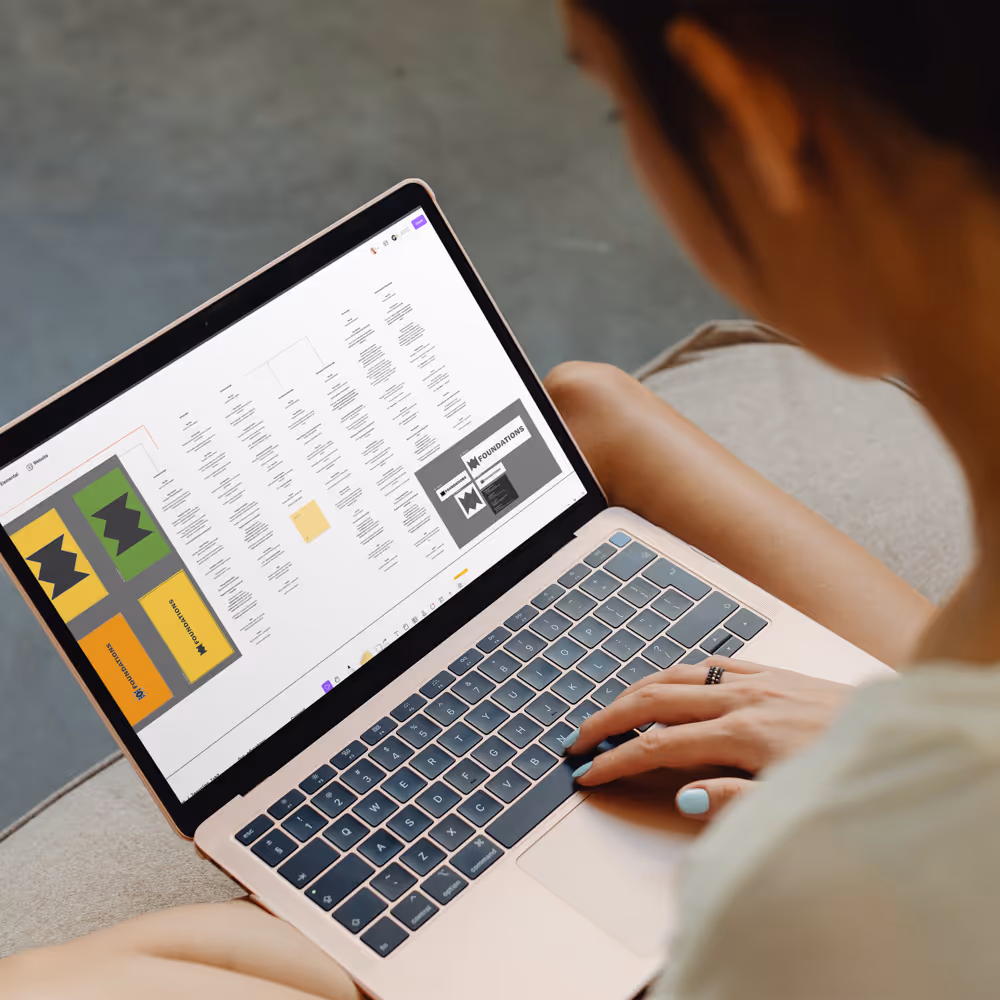 Person with light blue nail polish working on a laptop displaying a complex flowchart or organizational chart on screen.