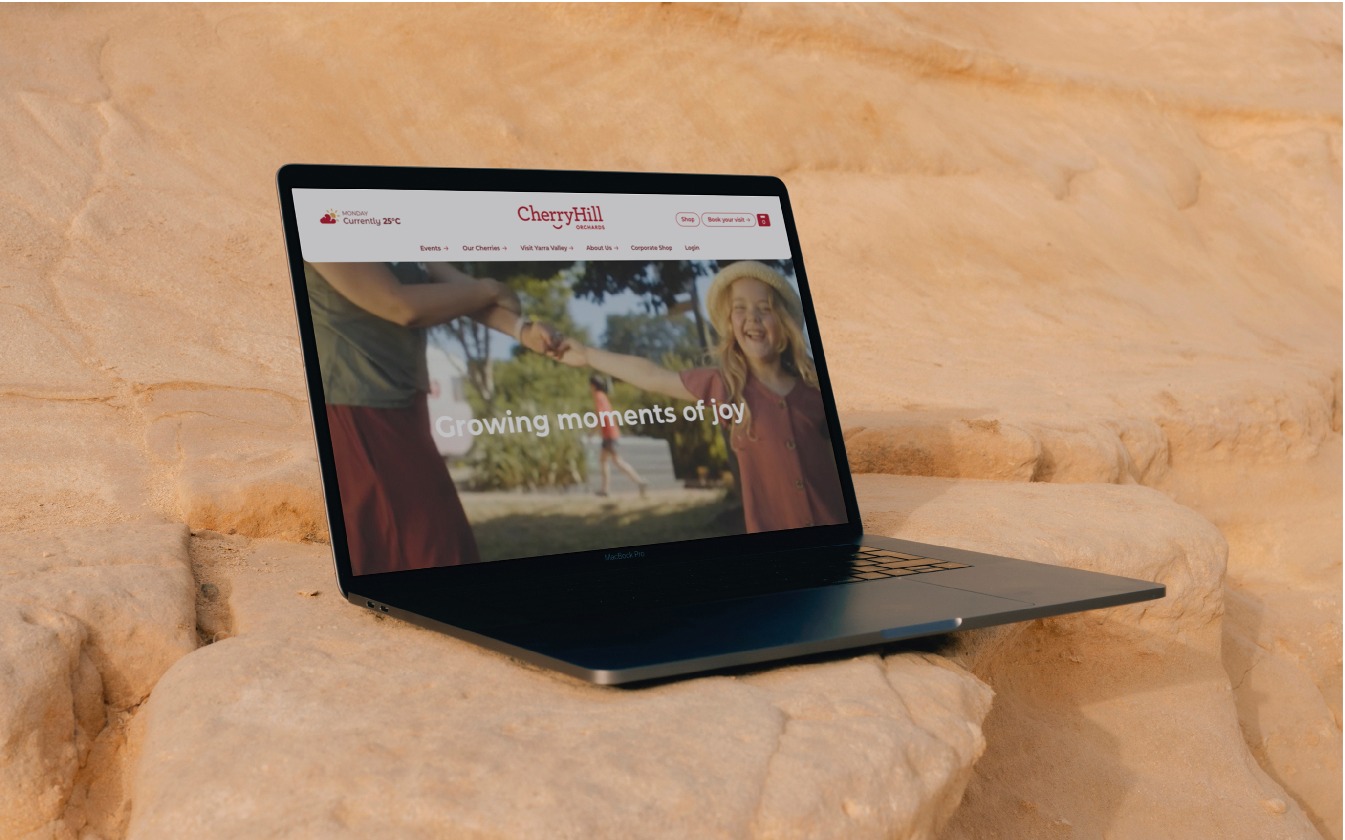 CherryHill website home page shown on an open laptop screen, sitting on sandstone.