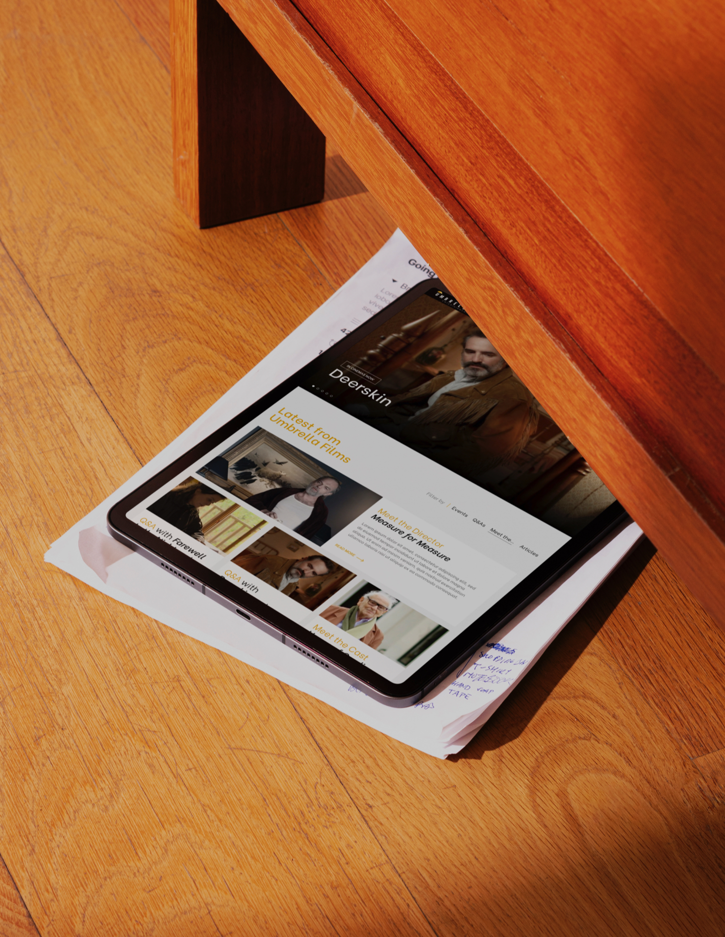 Close up of the Umbrella Entertainment website shown on a tablet on a wooden floor under a table.