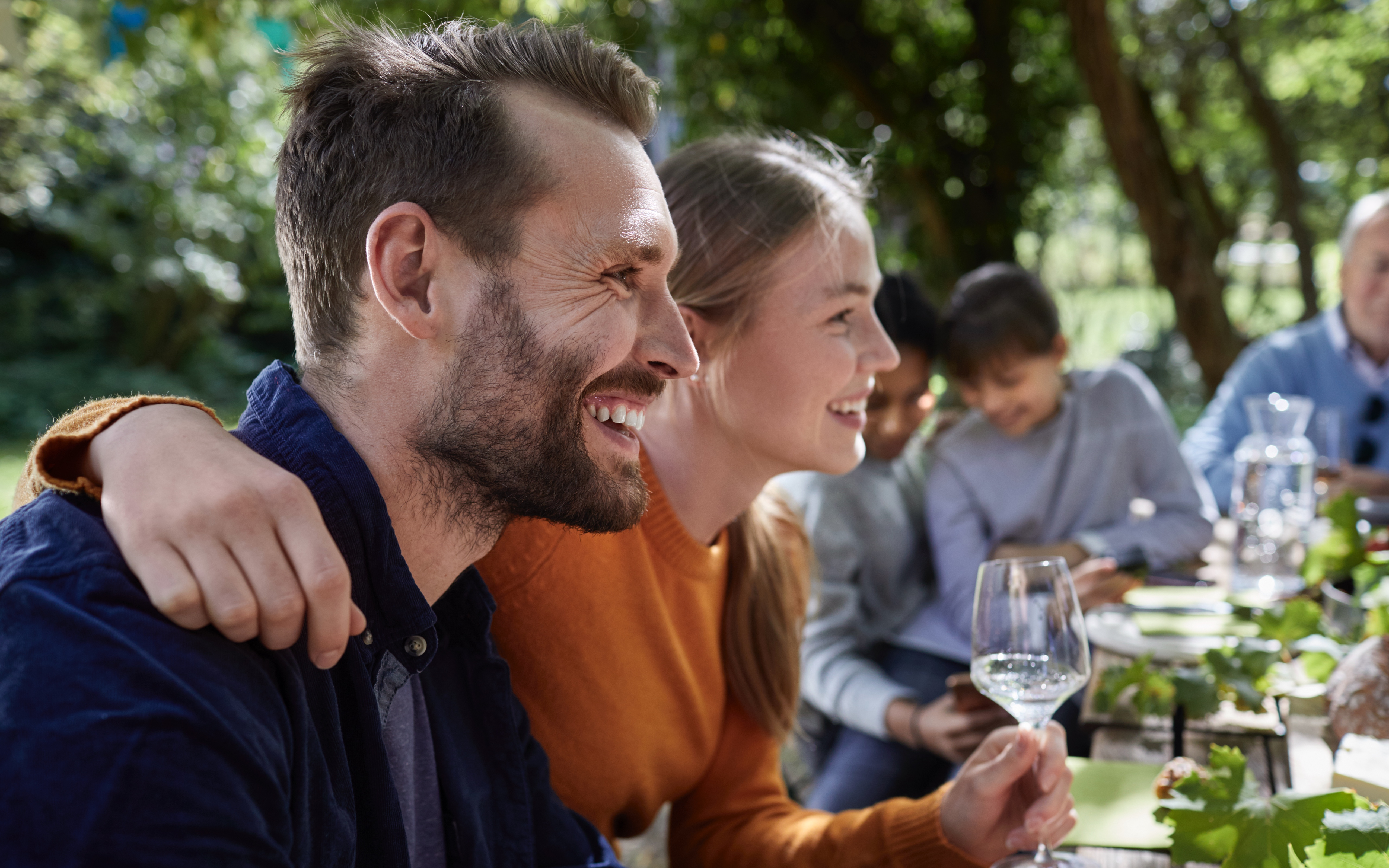 Man and woman smiling and listening to an unpictured person in a group setting.