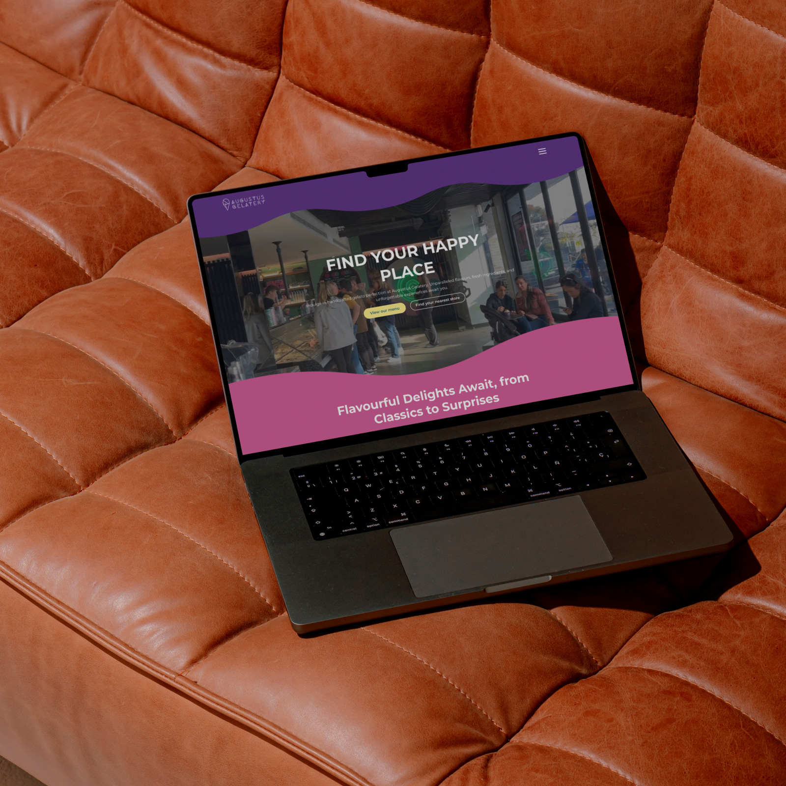 Augustus website shown on a laptop screen, placed on a leather couch.