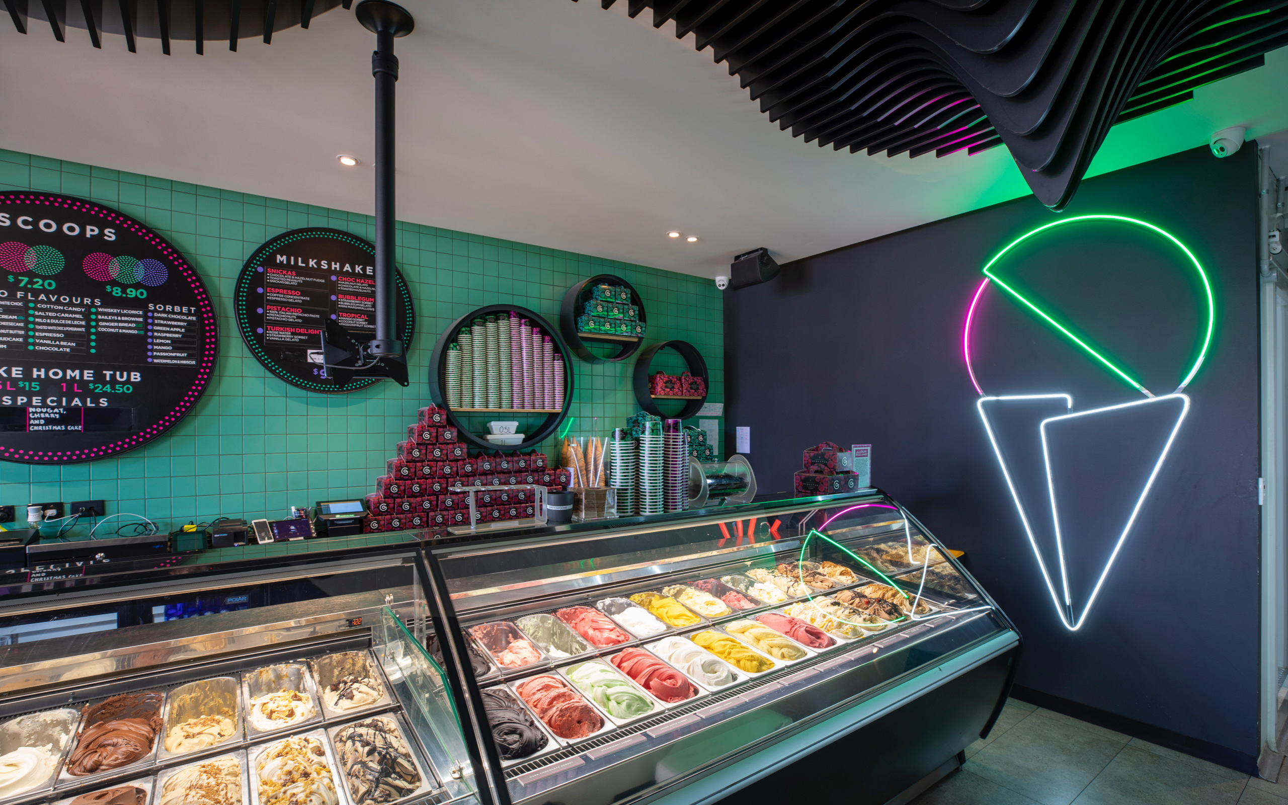 Interior of Augustus Gelatery store, with large cabinet full of gelato, and a neon gelato logo on the wall.