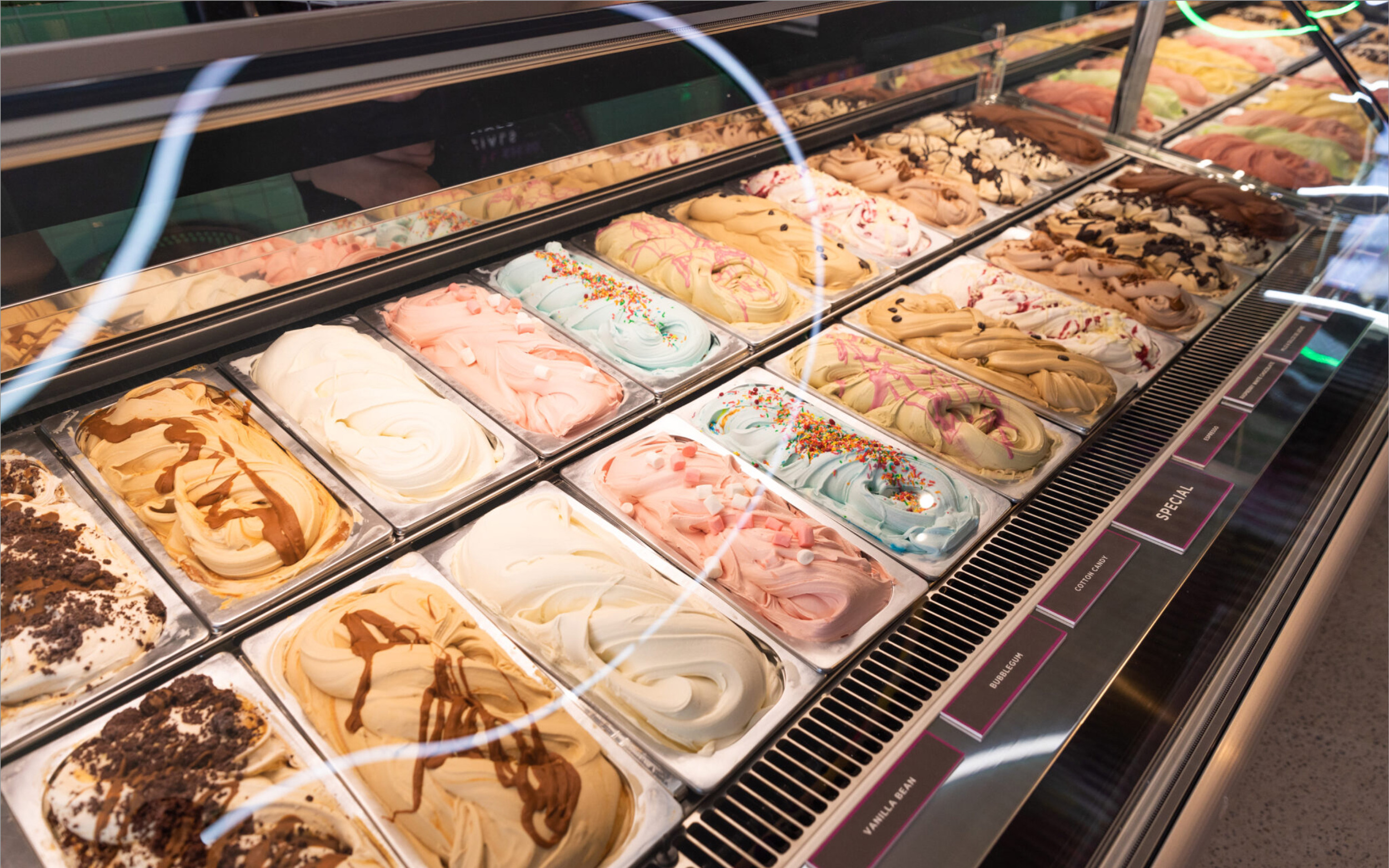 Cabinet of full tubs of gelato, showing many different flavours.