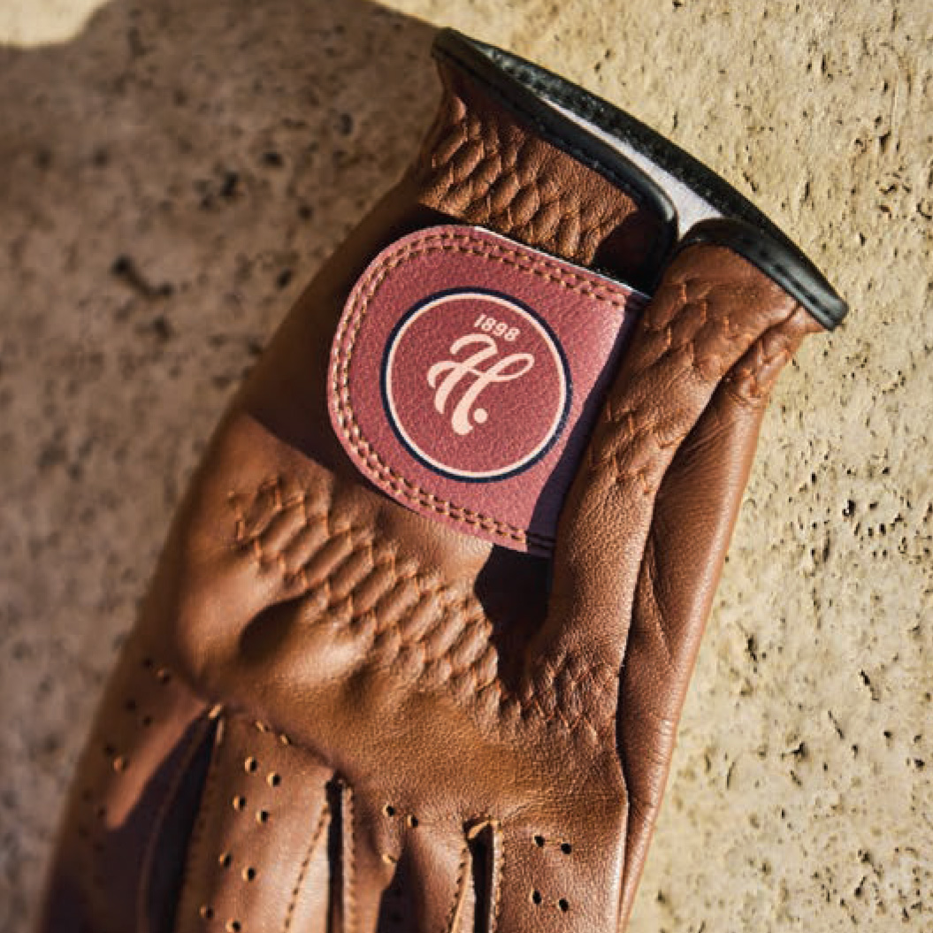 Close up detail shot of brown leather golf glove with Haskell logo on the strap.