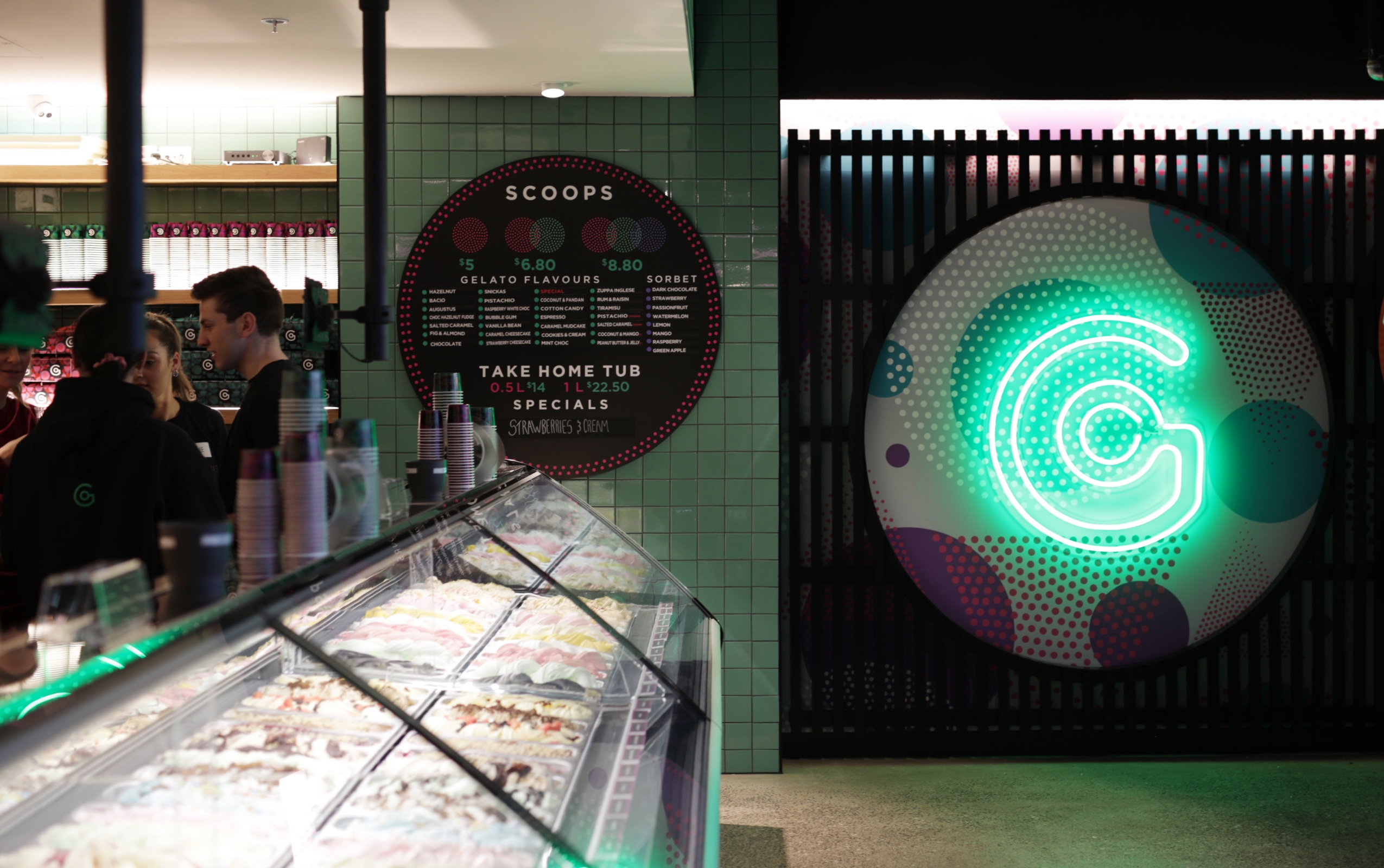 Interior of Augustus Gelatery store, with cabinet full of gelato and large neon logo on the wall.