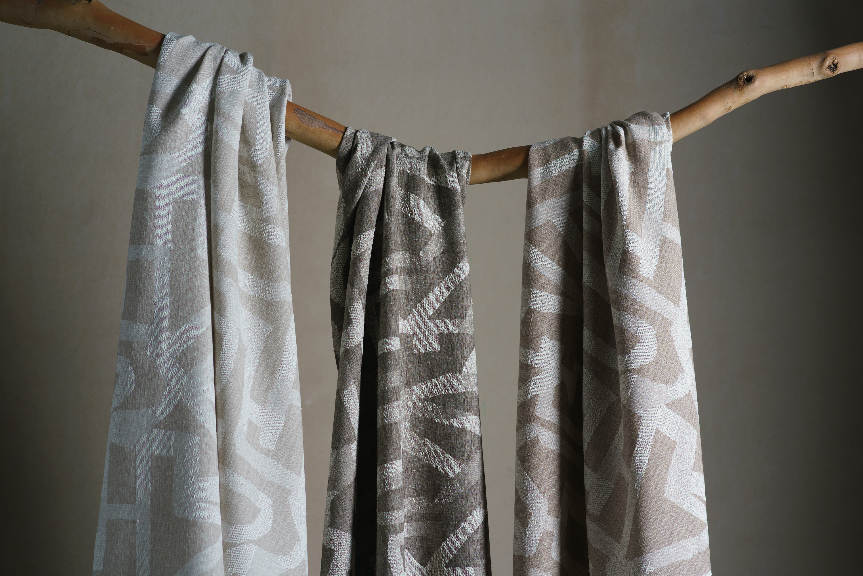 Three patterns fabrics hanging over a bendy branch.