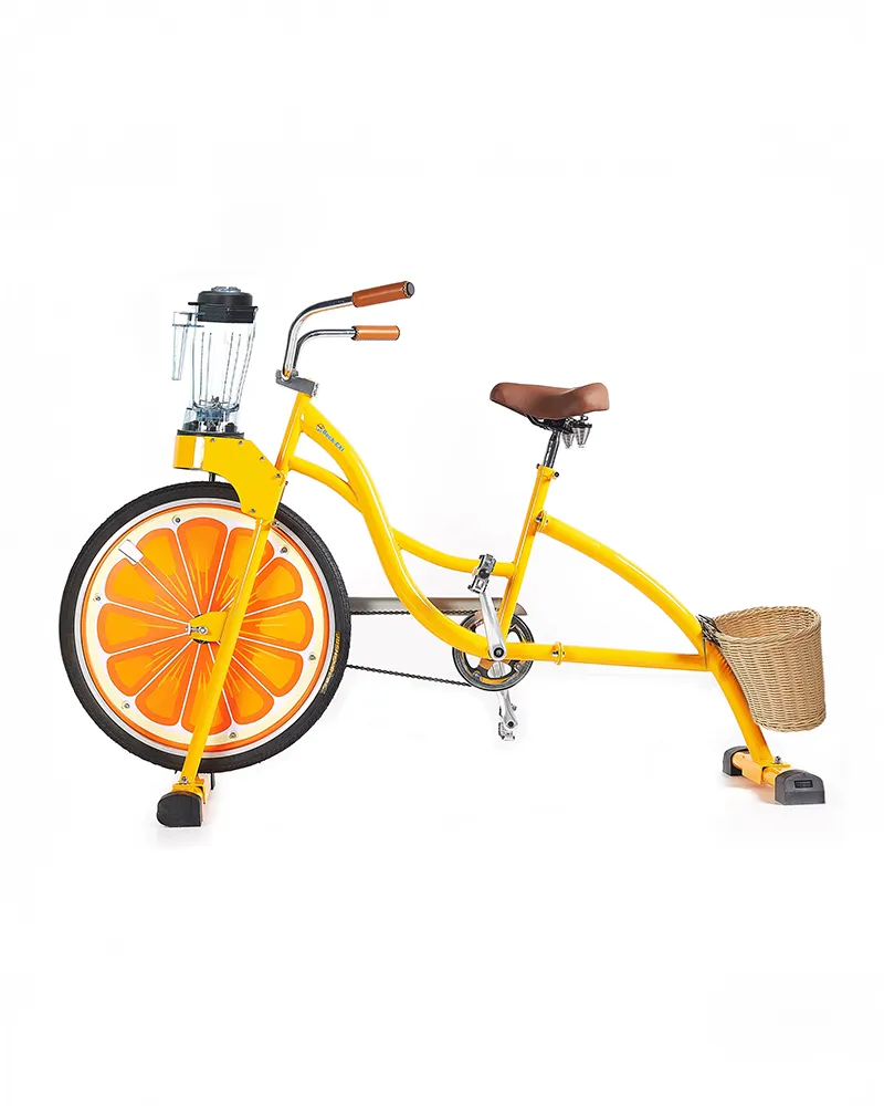 Geel indoor hometrainerfiets met een voorwiel in de stijl van een sinaasappel en een blender gemonteerd op het stuur.