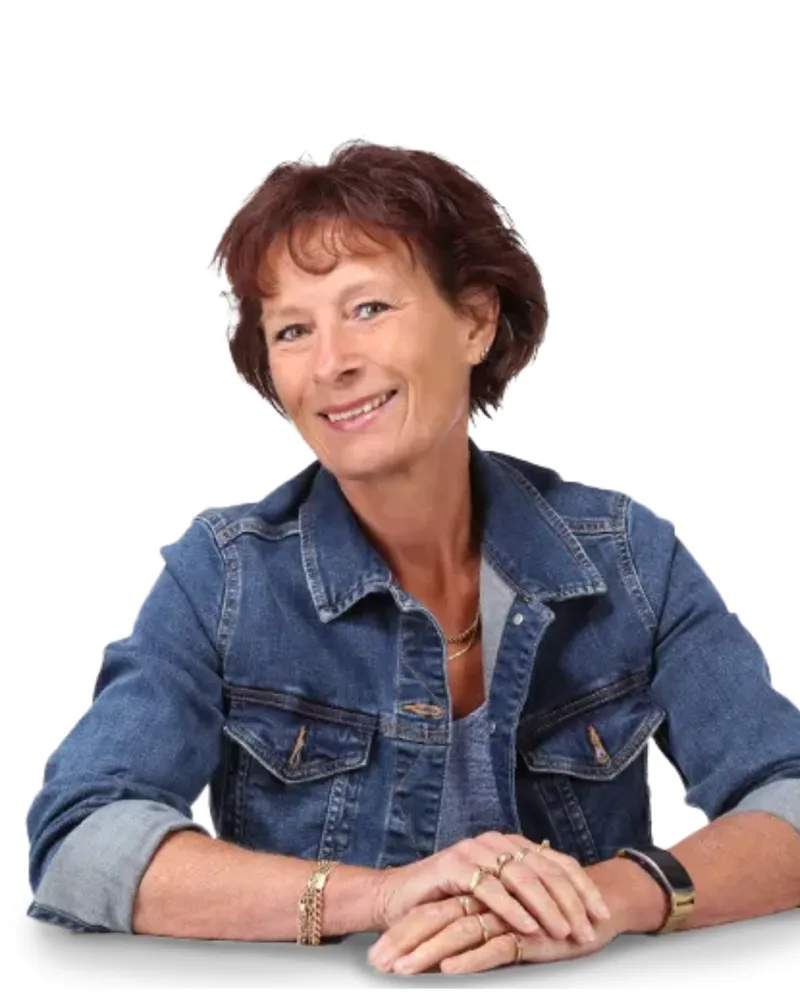 Vrouw met kort bruin haar glimlacht en draagt een spijkerjasje met opgerolde mouwen.