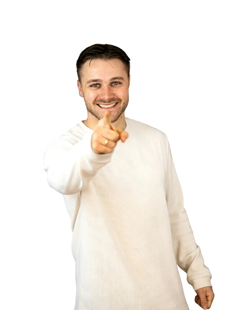 Lachende man wijst met zijn vinger naar de camera voor een bakstenen muur.