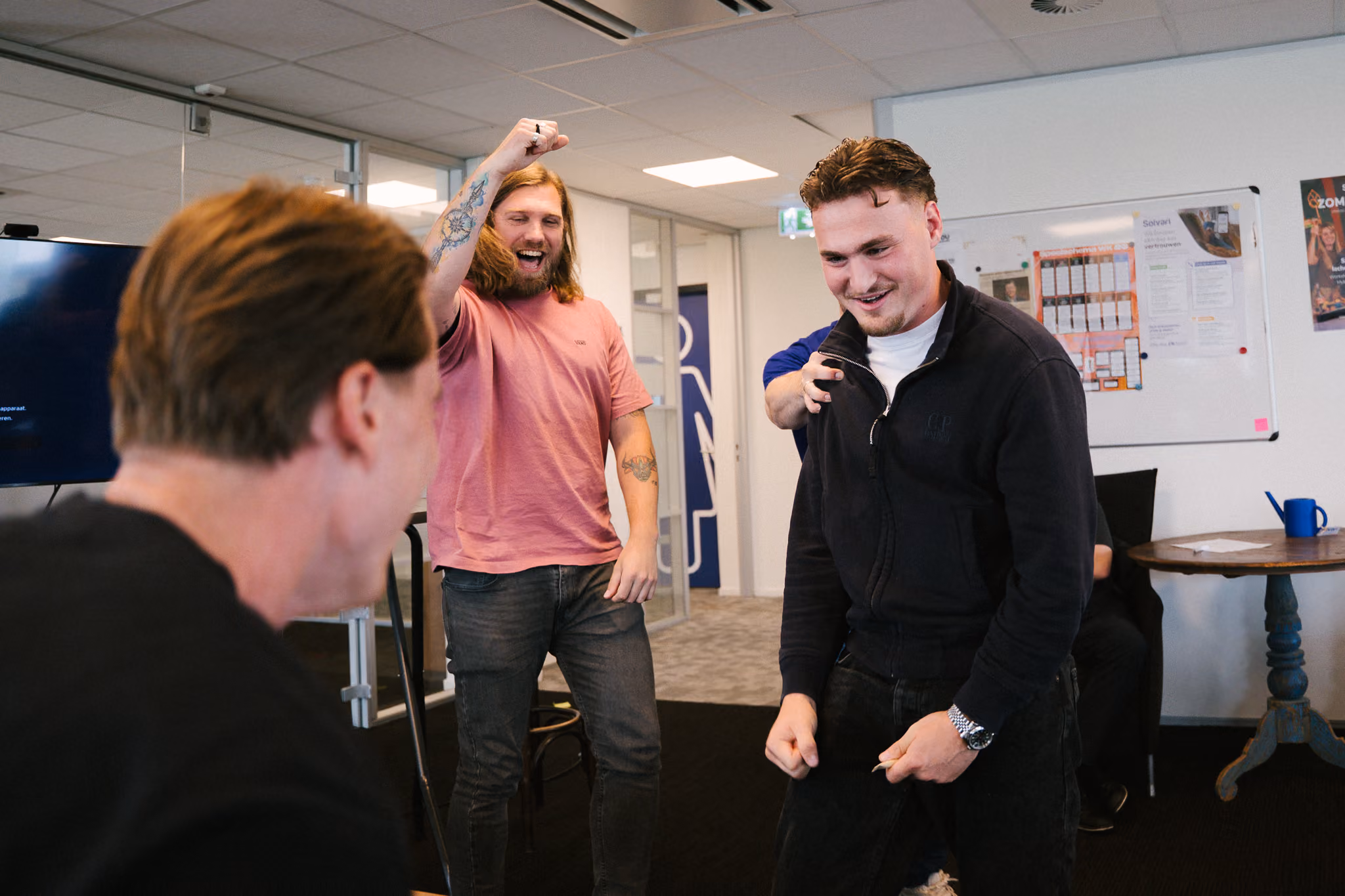 Uitgelaten sfeer op kantoor: collega's lachen en juichen tijdens een teamactiviteit op kantoor.