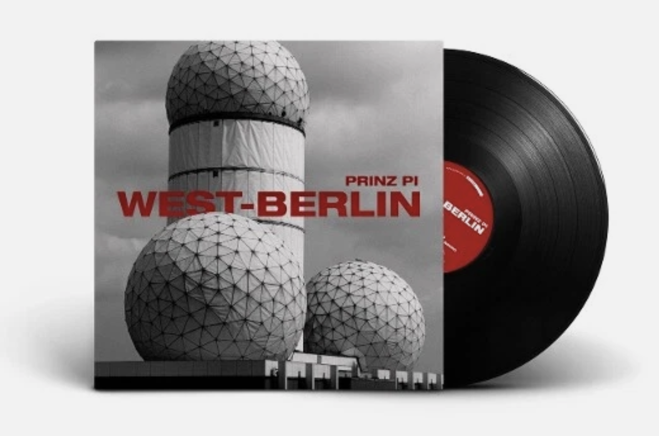 Vinyl-Schallplatte, die teilweise hinter einem Albumcover mit den Radartürmen des Teufelsbergs in Berlin und roter Schrift „Prinz Pi – West-Berlin“ zu sehen ist.