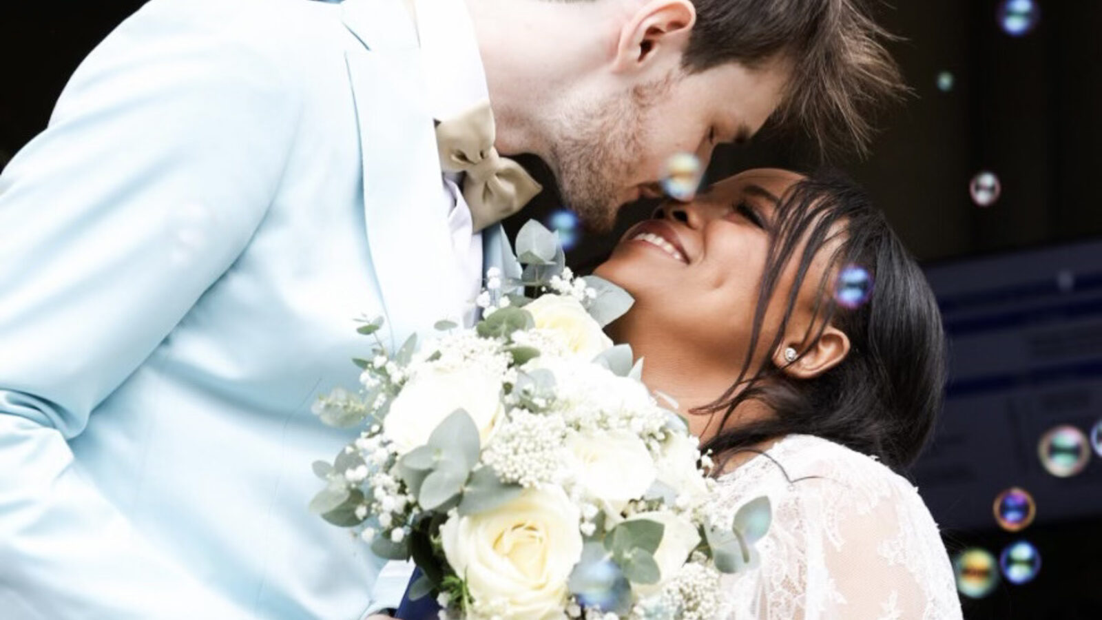 Couple de mariés souriants entourés de bulles, capturant un moment authentique lors de leur cérémonie