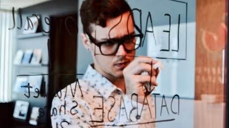 Man writing on glass board, working on a data project