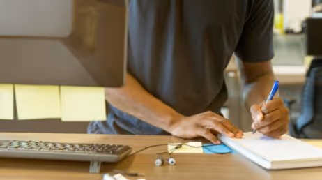 Person taking notes while working at a standing desk