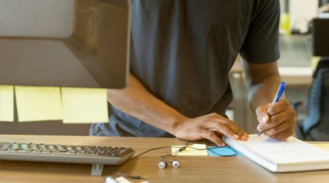 Person taking notes while working at a standing desk