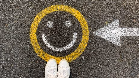 Yellow smiley face on asphalt with white arrow pointing right
