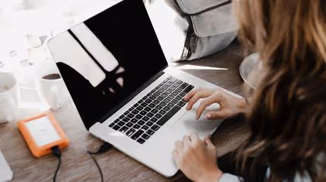 Woman working on laptop with external hard drive attached