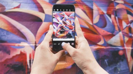 Person taking photo of colorful graffiti mural on phone