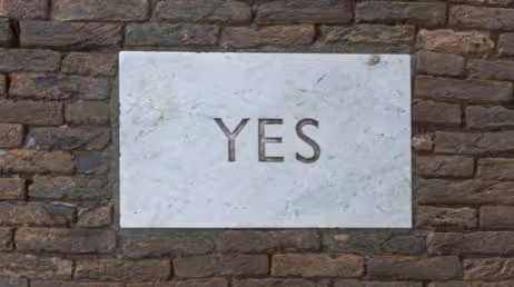 Marble stone with YES engraving on brick wall