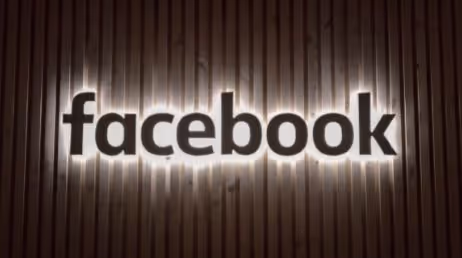 Illuminated Facebook logo on wooden backdrop