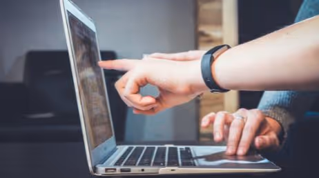 Hands pointing at a laptop screen during collaboration