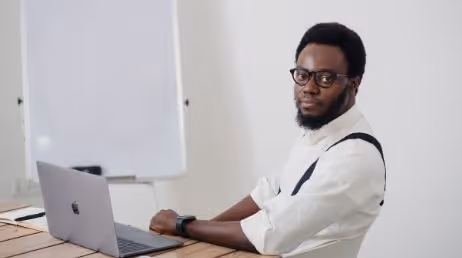 Man with glasses sitting at a desk with a laptop