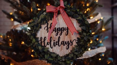 Wreath with "Happy Holidays" sign on a Christmas tree.