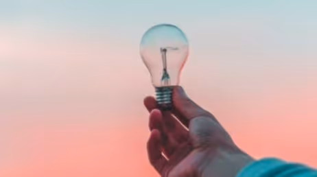 Men holding a lightbulb at sunset at background