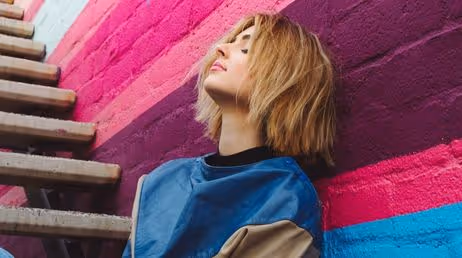 Woman sitting against colorful mural wall