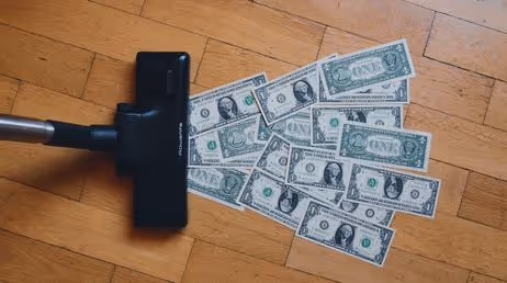 Vacuum cleaner with dollar bills on floor