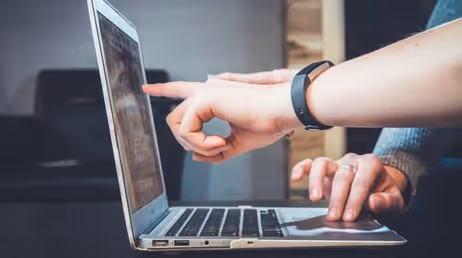 Hands pointing at a laptop screen during collaboration