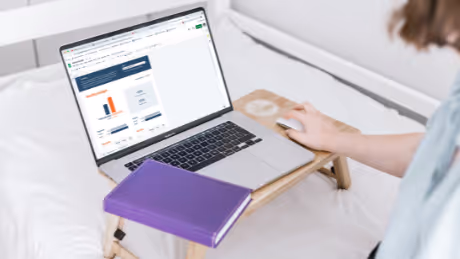 Person working on a laptop in bed with analytics on screen