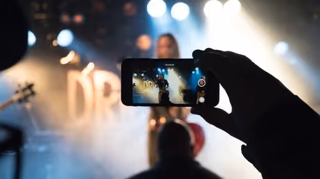 Person capturing a concert performance on their smartphone