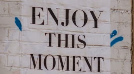 Poster with the text 'Enjoy this Moment' on a wall
