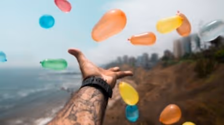 Colorful balloons in mid-air over a coastal landscape