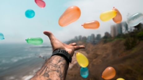 Colorful balloons in mid-air over a coastal landscape