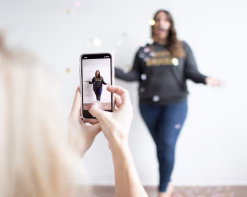 Person recording another woman with a smartphone while confetti falls