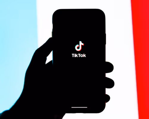 Hand holding phone displaying TikTok logo with colorful background